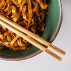 pair of momofuku chopsticks resting on noodle bowl