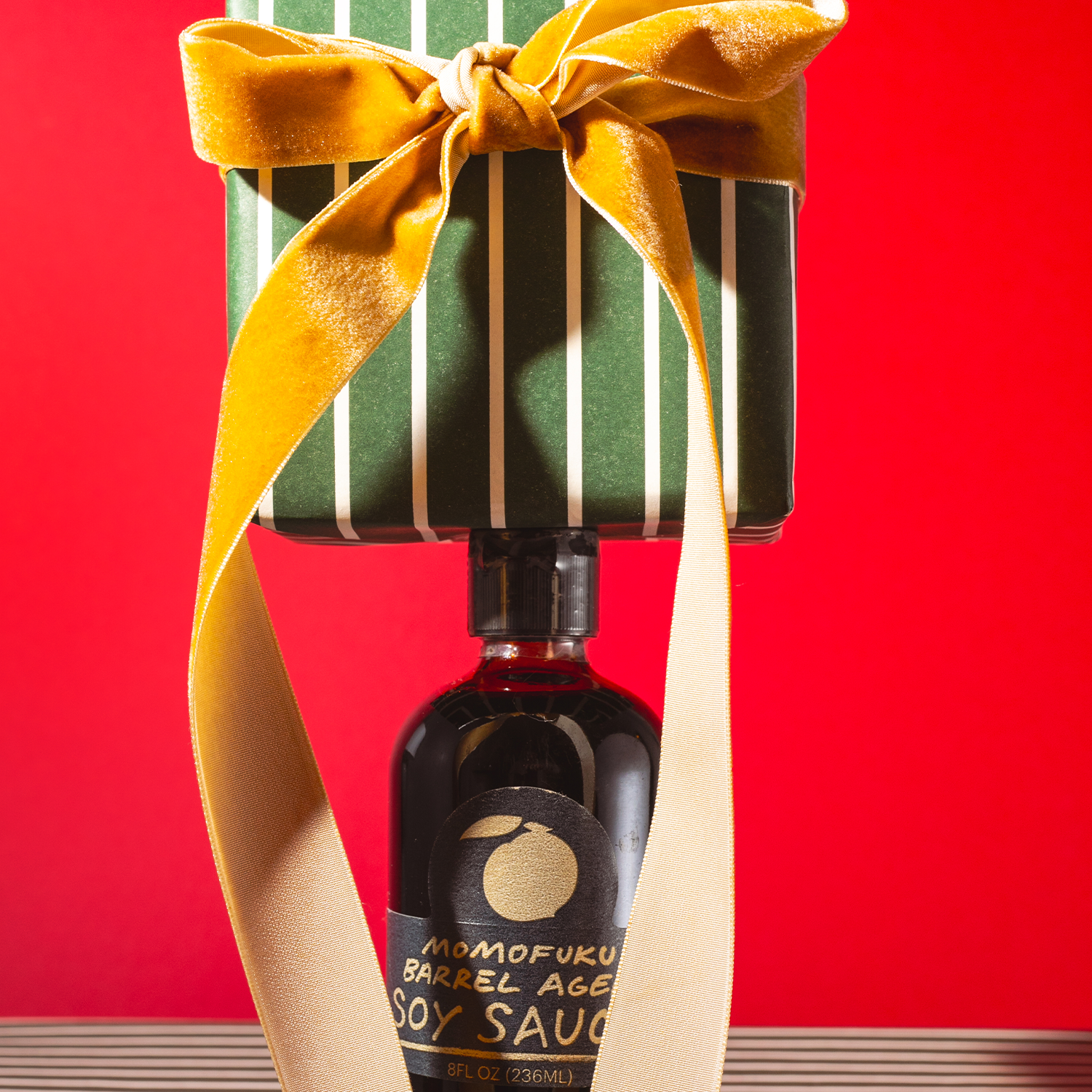 Bottle of soy sauce with a decorative bow on a red background
