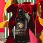 Bottle of Momofuku Barrel Aged Soy Sauce with a red ribbon on a decorative background
