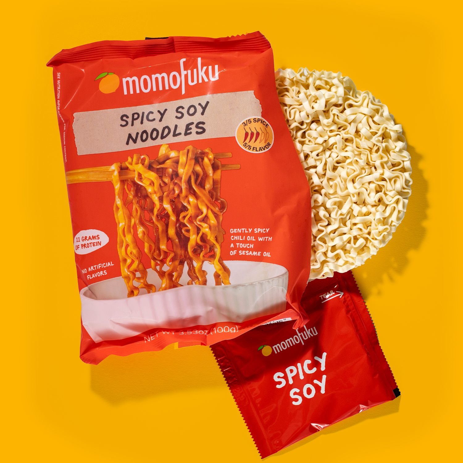Momofuku Spicy Soy Noodles package with noodles on a yellow background